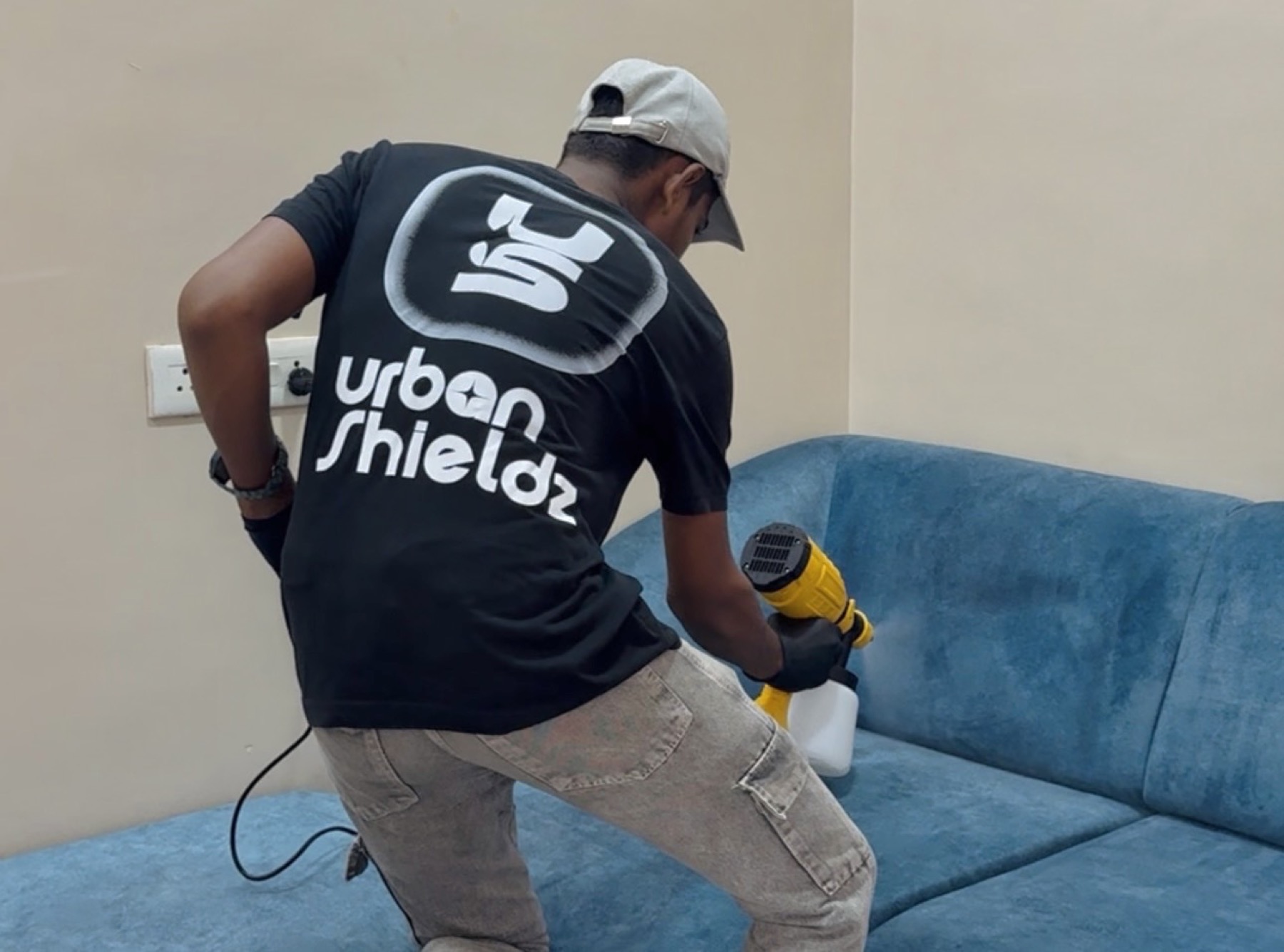 Urban Shieldz specialist applying fabric nano coating to a blue sofa.
